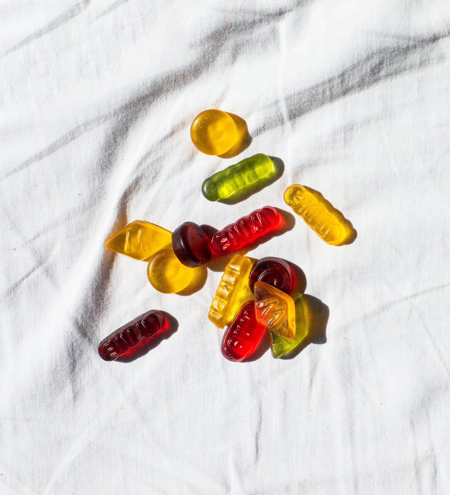 Bonbons éparpillés sur un drap blanc illustrant l’addiction au sucre raffiné, les envies de sucre des patients, fatigue, baisse de moral et prise de poids.