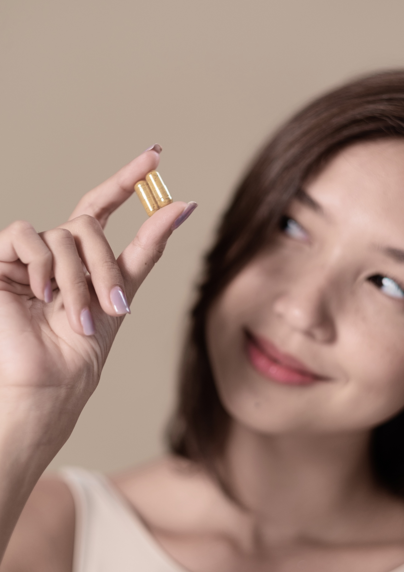 Femme tenant deux gélules de notre cure Sweet Control entre ses doigts – complément alimentaire contre les fringales sucrées.