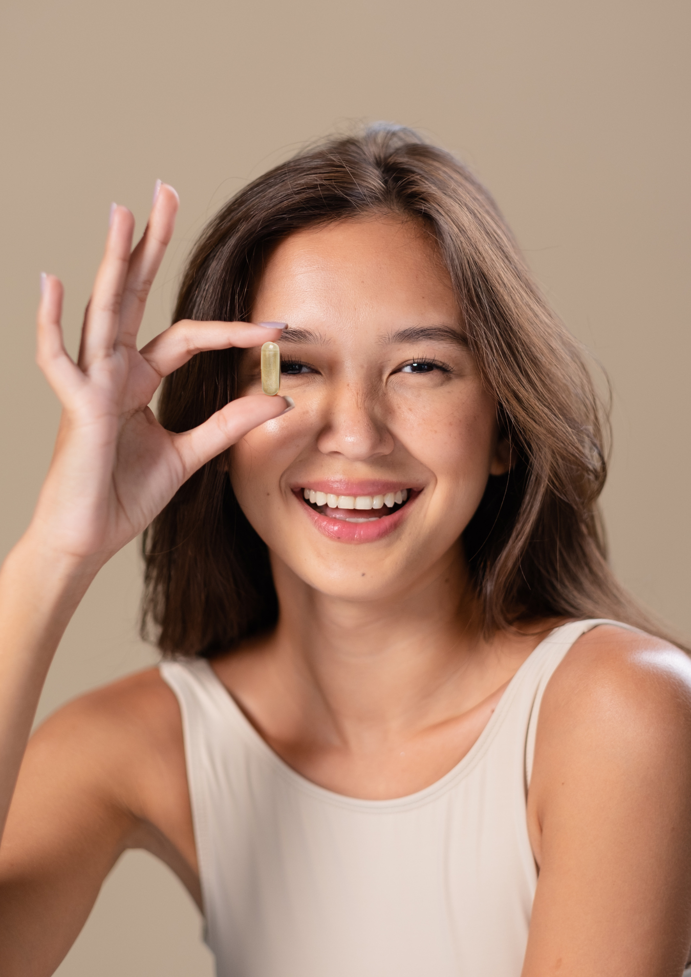 Femme souriante tenant une gélule de notre cure de complément alimentaire Sweet Control entre ses doigts. Permet de réguler la glycémie et les envies sucrées.