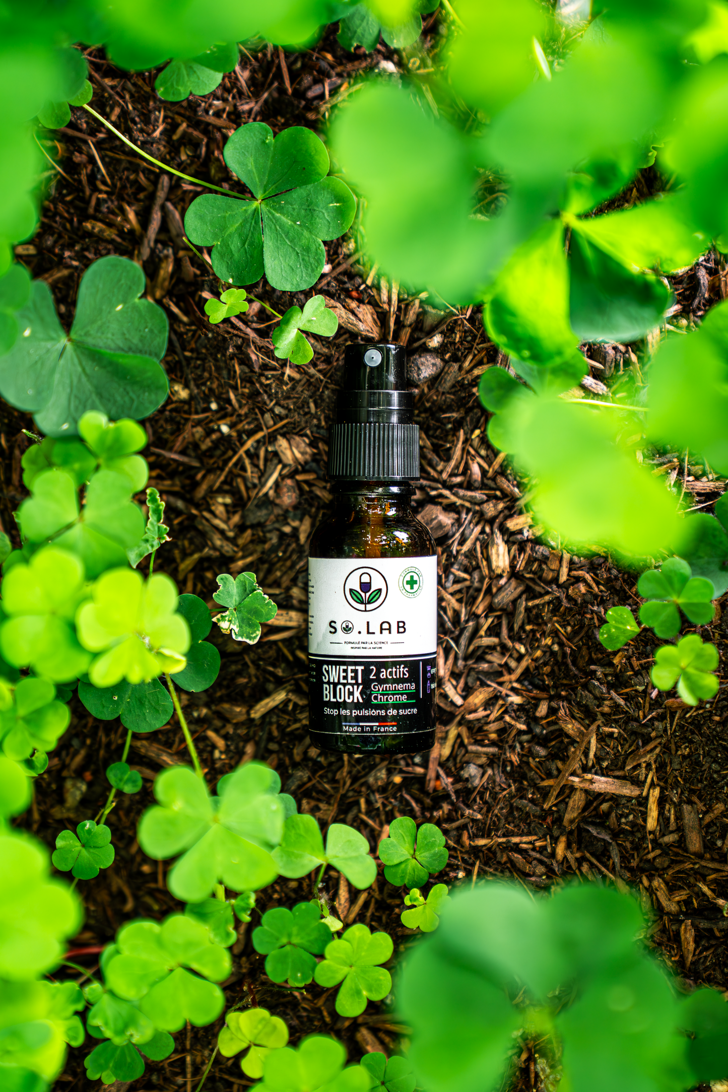 Mise en scène du spray anti-sucre Sweet Block dans la nature avec des trèfles symbolisant le naturel.